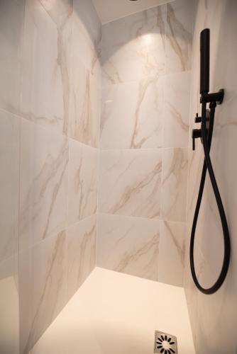 La salle de bains est pourvue d'une douche et de murs en marbre blanc. dans l'établissement Wonderful flat center of Paris, à Paris