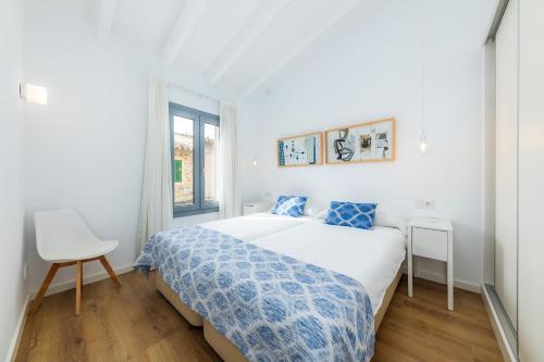 een witte slaapkamer met een bed en een stoel bij Sa Botigueta Petit in Artá