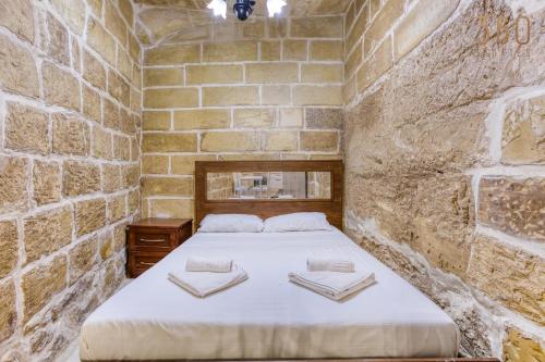 a bedroom with a bed in a brick wall at The Blue Village Suites by 360 Estates in Żejtun