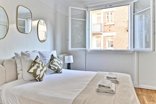 sypialnia z dużym białym łóżkiem z 2 lustrami w obiekcie Apparement à 5 minutes de Paris - Neuilly w mieście Neuilly-sur-Seine
