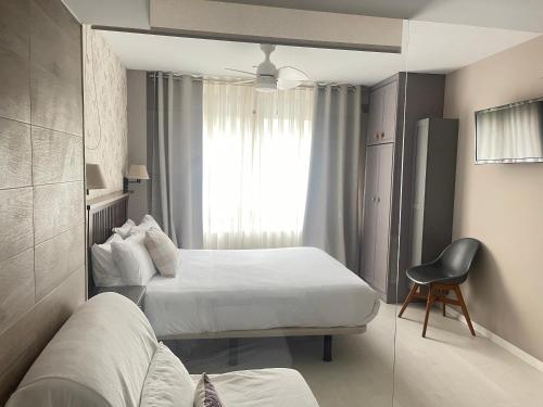 a hotel room with two beds and a chair at Apartamentos Las Vegas in Ribadesella