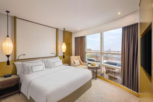 um quarto de hotel com uma cama e uma grande janela em Melia Hanoi em Hanói