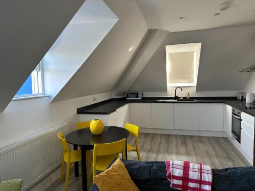 チェルムスフォードにあるStunning 2-Bed Apartment in Chelmsfordのキッチン(テーブル、黄色い椅子付)