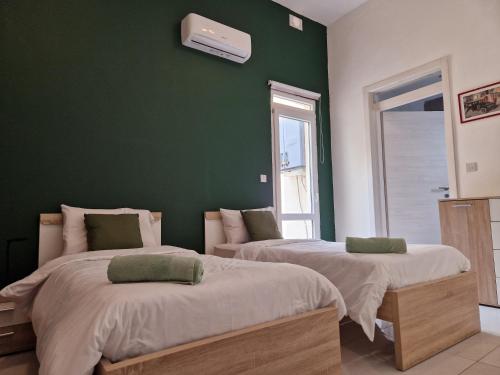 two beds in a room with a green wall at District in Victoria