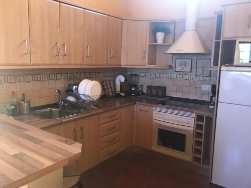 a kitchen with wooden cabinets and a white refrigerator at Una casa con vistas in La Caleta