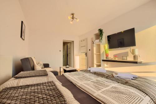 two beds in a room with a tv on the wall at Dom Camelowo Willa in Brenna