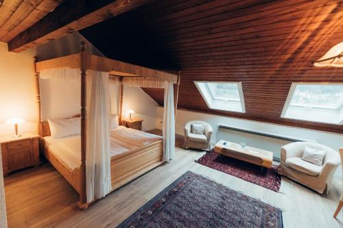 a bedroom with a canopy bed and two chairs at Gasthof Hotel zur Post in Egloffstein