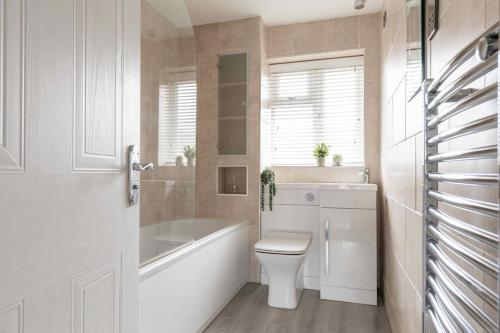 ein Badezimmer mit einer Badewanne, einem WC und einem Waschbecken in der Unterkunft Evergreen Cottage Orsett in Orsett