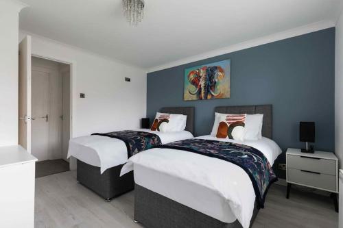 two beds in a bedroom with blue walls at Evergreen Cottage Orsett in Orsett