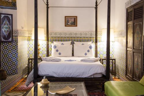 a bedroom with a four poster bed with white sheets at Ryad El Borj in Marrakech