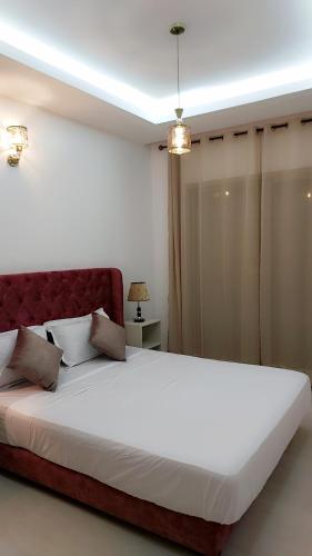 a large white bed with a red headboard in a bedroom at Appartement Perla - Costa Bouznika in Bouznika