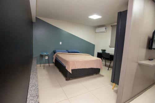 a bedroom with a bed and a blue wall at Jahu Center Plaza Flats in Jaú