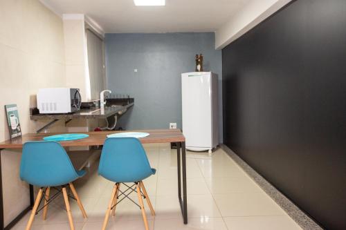 a kitchen with a table and two blue chairs at Jahu Center Plaza Flats in Jaú