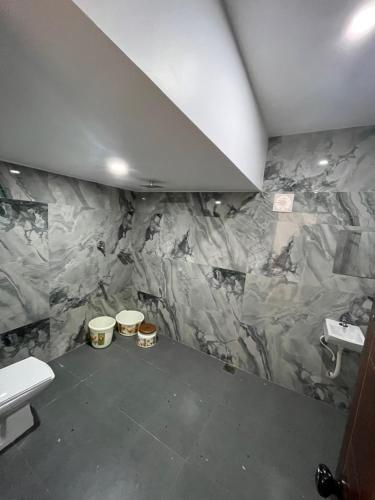 a bathroom with a marble wall with buckets on the floor at LOVESHORE Homestay in Kollam