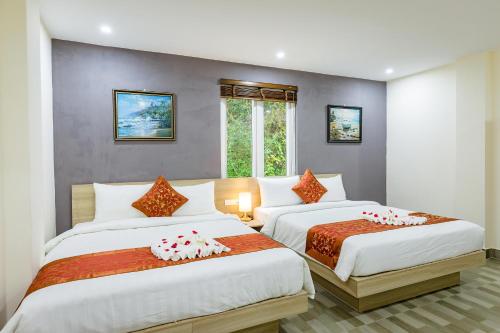 a bedroom with two beds and a window at Cat Ba Violet Hotel in Cat Ba