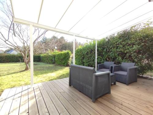 a wooden deck with chairs and a pergola at Logement au calme avec jardin proche de Vannes in Elven
