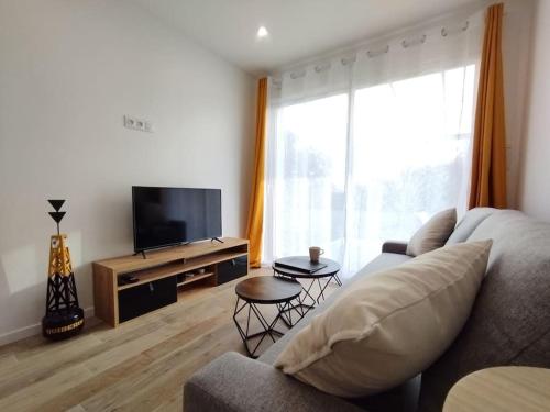 sala de estar con sofá y TV de pantalla plana en Logement au calme avec jardin proche de Vannes, en Elven