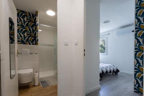 - une salle de bains avec toilettes et un lit dans une chambre dans l'établissement Le Petra - Appt climatisé proche de la plage, à Ajaccio