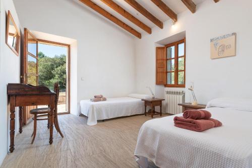 a white room with a piano and two beds at Son Pastor in Artá