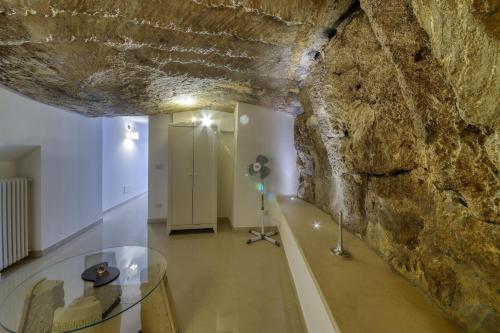 Habitación con mesa de cristal y pared de piedra. en La Cattedrale Apartments&Suite - Affitti Brevi Italia, en Gravina in Puglia
