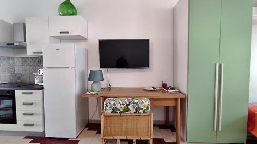 a kitchen with a refrigerator and a desk with a television at L' Appoggio - Monolocale Eco-sostenibile A Due Passi Dal Centro Storico in Corsano