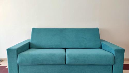 a blue couch sitting in a living room at L' Appoggio - Monolocale Eco-sostenibile A Due Passi Dal Centro Storico in Corsano