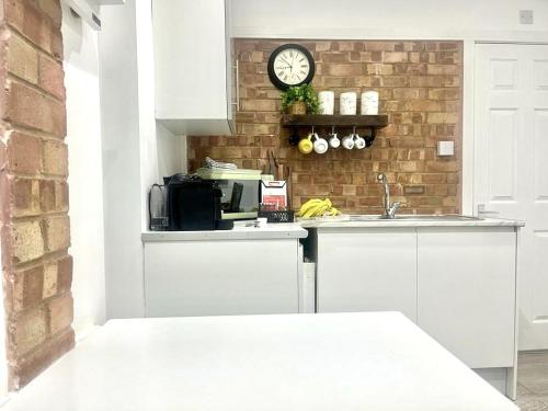a kitchen with a clock on a brick wall at Nice and Cosy Large Studio near Luton Airport in Luton