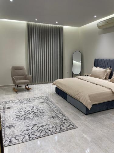 1 dormitorio con 1 cama, 1 silla y 1 alfombra en شقة فاخرة دور ارضي مدخل خاص وباركنج سيارة en Riyadh Al Khabra