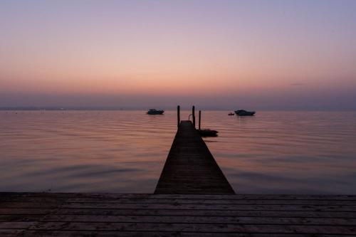 a dock with boats in the water at sunset at Villa Pioppi Hotel in Sirmione