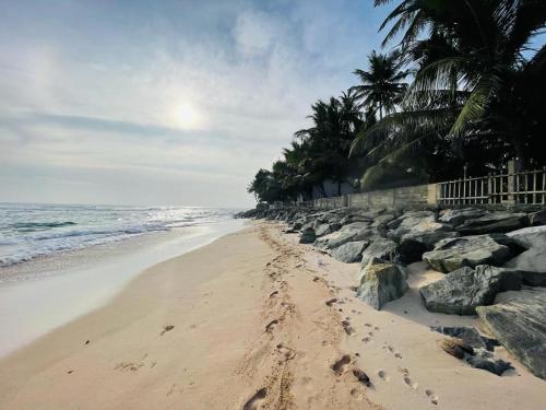 a beach with footprints in the sand and rocks at Rainbow Surf Beach in Koggala