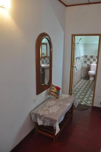 a bathroom with a mirror and a table and a toilet at Sea Breeze Inn Talalla in Talalla