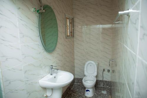 W łazience znajduje się umywalka, toaleta i lustro. w obiekcie Cogent Apartments Single Rooms w Uyo