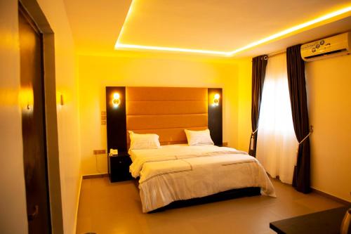 um quarto com uma cama grande num quarto amarelo em Cogent Apartments Single Rooms em Uyo