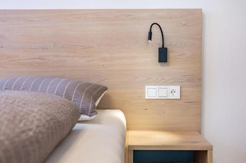 1 cama con cabecero de madera y interruptor de luz en Mountain Meadows Apt 2, en Valdaora
