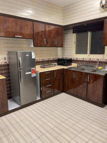 a kitchen with wooden cabinets and a stainless steel refrigerator at شقق مسك الفندقية MISK Apartments in Riyadh Al Khabra