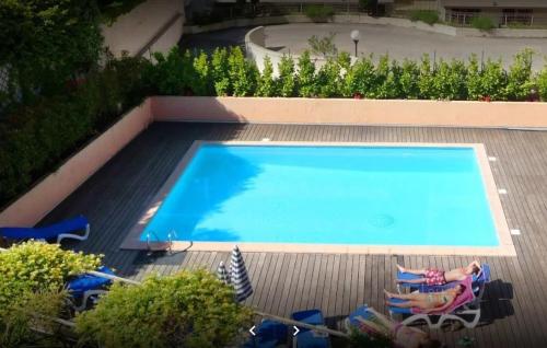 - une piscine avec 2 personnes assises dans des chaises à côté dans l'établissement Superbe Appartement avec terrasse 2 chambres, 4 à 5 couchages piscine, à deux pas des plages et de la Croisette, à Cannes