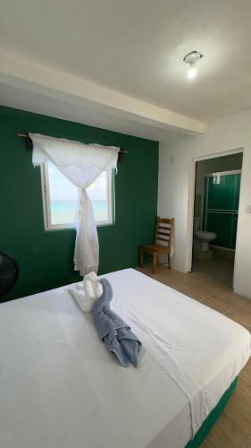 a bedroom with a white bed with a green wall at The Wave Hostel Corn Island in Corn Island