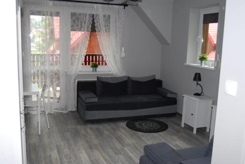a living room with a black couch and a window at Domek nad Muszynką in Muszyna