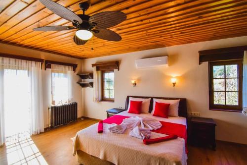 een slaapkamer met een groot bed en een plafondventilator bij Fethiye Kayaköy'de Özel Havuzlu Muhafazakar Villa Kaya Konak in Fethiye