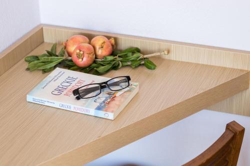 a book and glasses on a table with apples and leaves at Atlantis Hotel in Karpathos Town