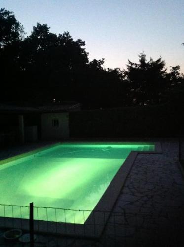 ein Schwimmbad in der Nacht mit grüner Beleuchtung in der Unterkunft villa familiale de caractere in Casteljaloux