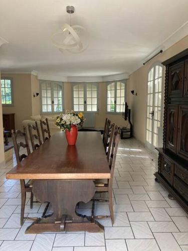 une table de salle à manger avec un vase de fleurs dessus dans l'établissement villa familiale de caractere, à Casteljaloux