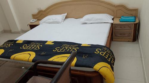 1 dormitorio con 1 cama y escritorio con colcha en The Royal Elite Guest House, en Jalandhar