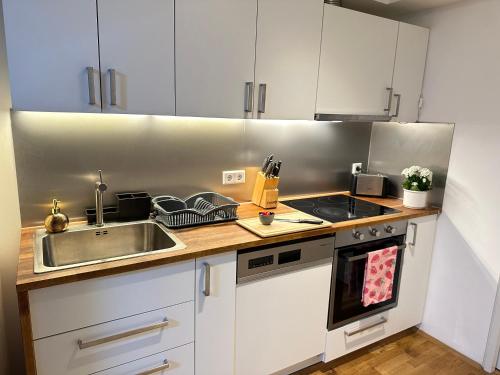 a kitchen with white cabinets and a sink at The Peaceful Garden Stay & Free Parking in Salzburg
