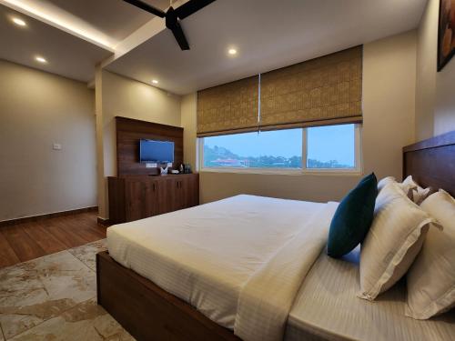 a bedroom with a large bed with a large window at Gee Resort & Heights in Idukki