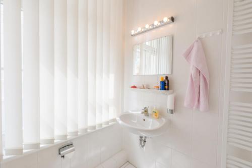 La salle de bains blanche est pourvue d'un lavabo et d'un miroir. dans l'établissement Appartementhaus Villa Norden, à Kühlungsborn