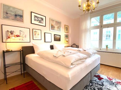 a bedroom with a large white bed and a chandelier at App. Melusine im Gartenhaus Villa Elisabeth in Heringsdorf