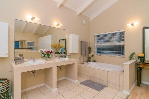 un bagno con due lavandini, una vasca e un grande specchio di Hot Tub Haven - Back up electricity Plett a Plettenberg Bay