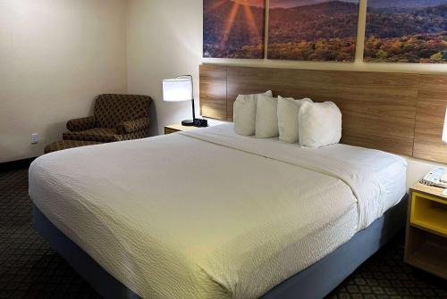 a hotel room with a large bed and a chair at Days Inn & Suites by Wyndham Eunice in Eunice