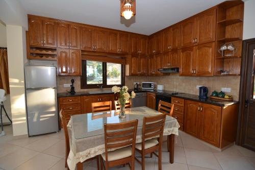 a kitchen with wooden cabinets and a table with chairs at Kalli Villa in Pomos